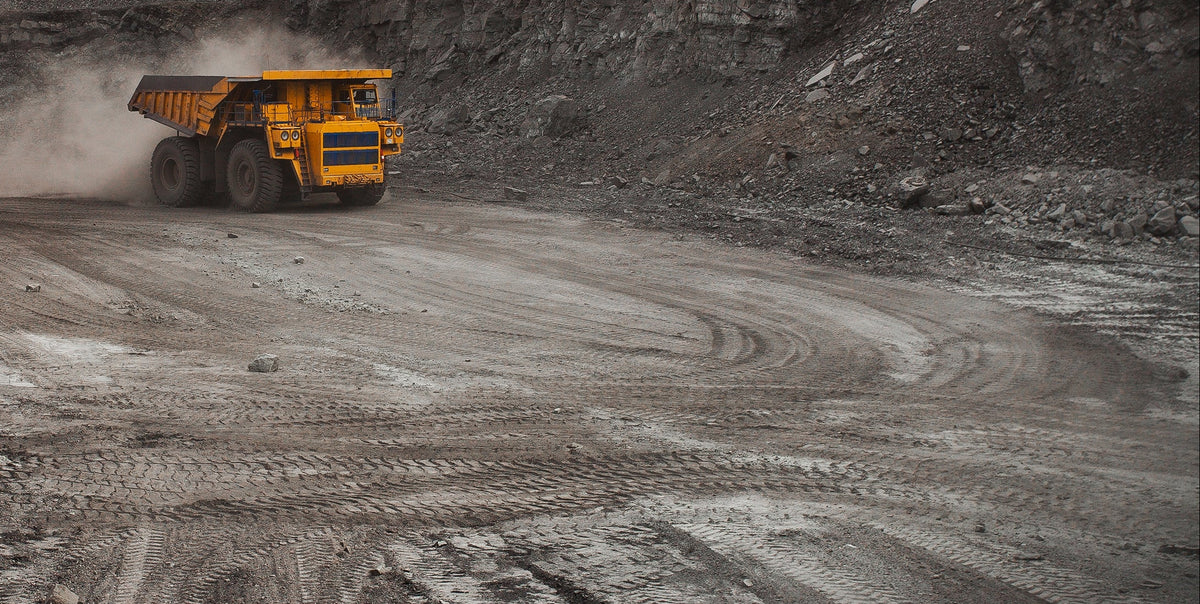 Yellow mining truck on a dusty road in a mining site