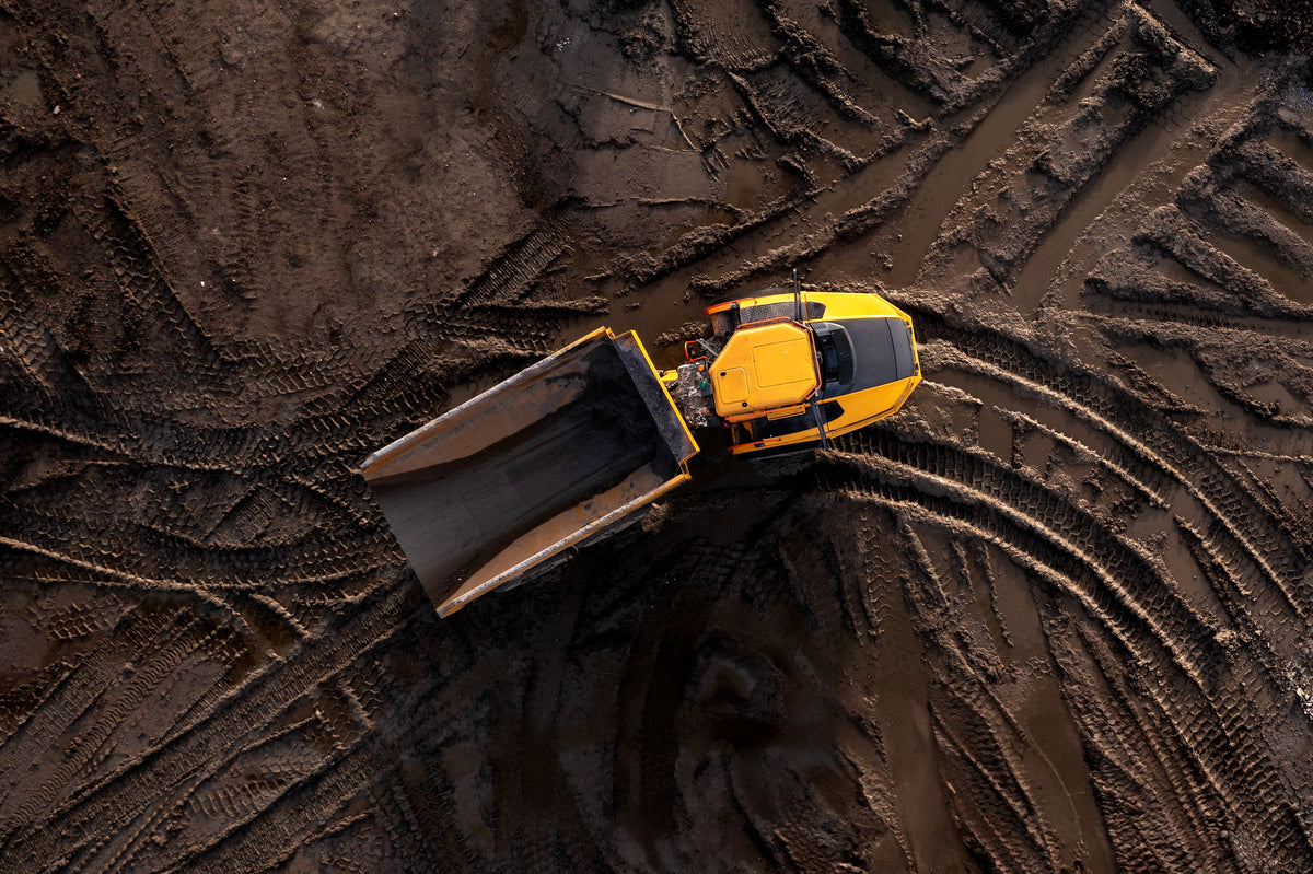 Yellow bulldozer on a muddy field from an aerial perspective